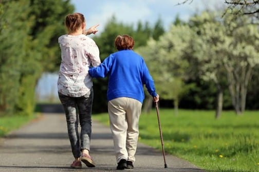 Une personne accompagne en promenade une personne agée.