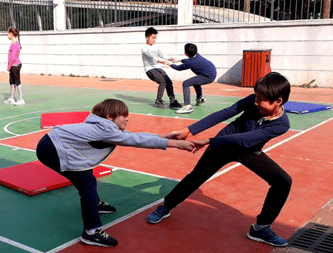 Deux enfants qui se tiennent les mains et qui essaient de chacun tirer l'autre vers soi.